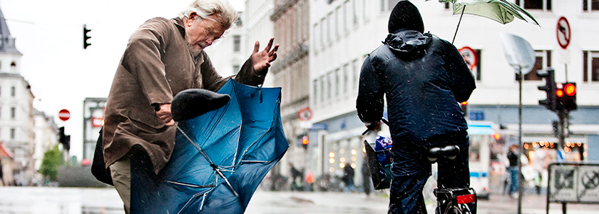 To mennesker med paraplyer i modvind
