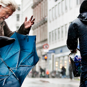 To mennesker med paraplyer i modvind