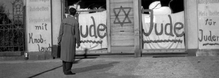 Person foran vinduer, hvor nogen har skrevet jude